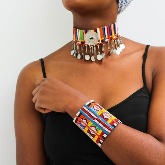 Person wearing a colorful beaded choker and bracelet on a plain background
