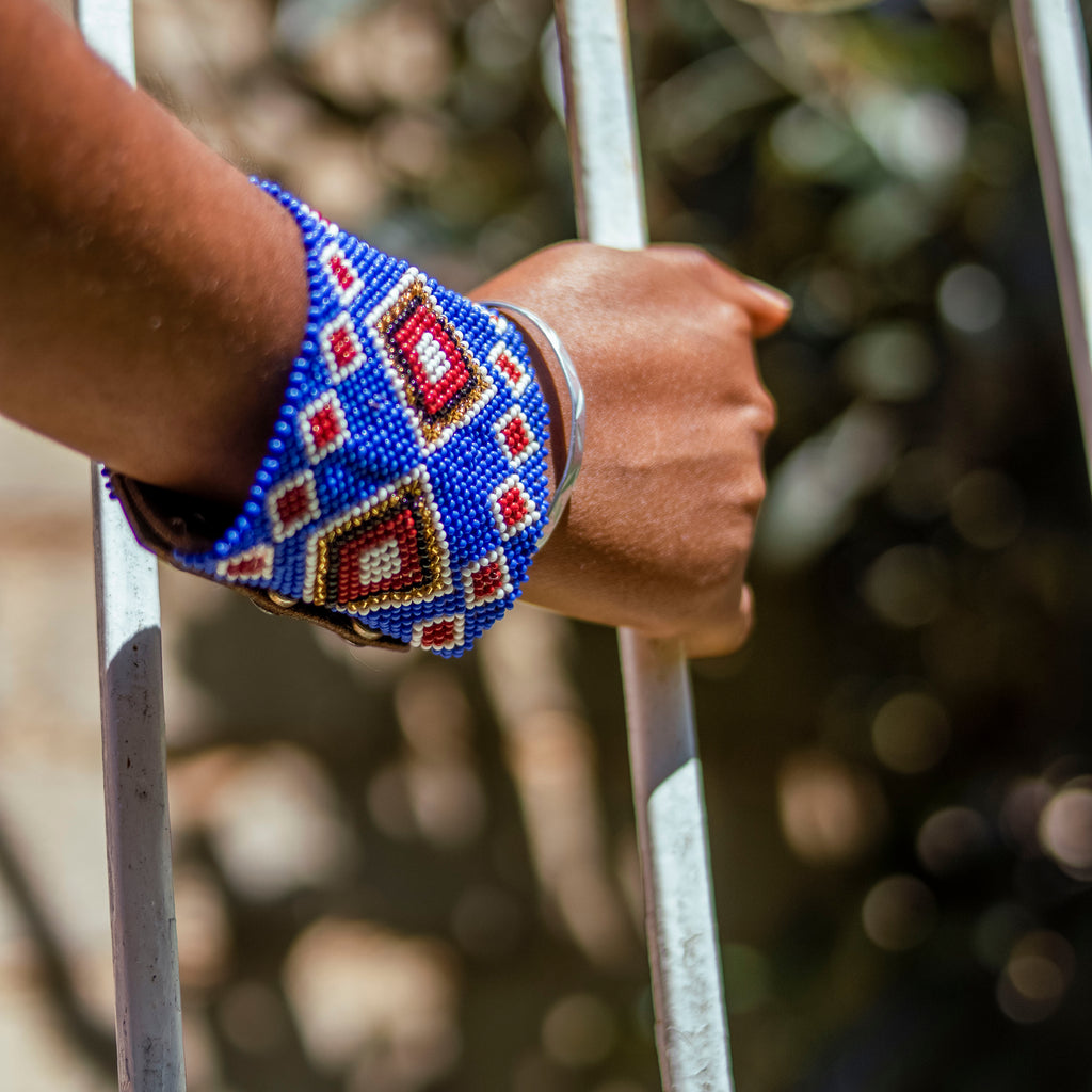 Hand wearing a colorful beaded bracelet from enkanashe africa on a metal gate