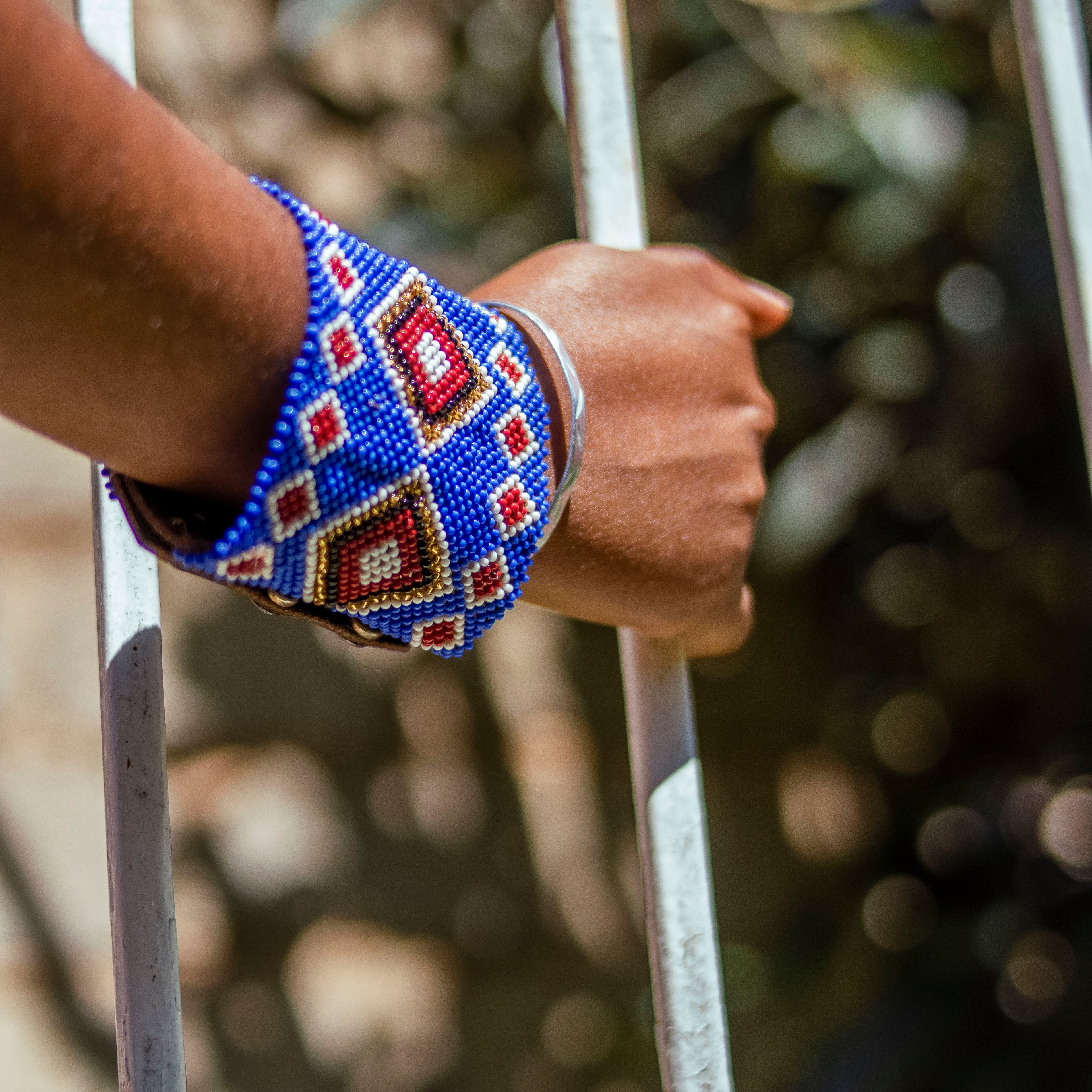 Hand wearing a colorful beaded bracelet from enkanashe africa on a metal gate
