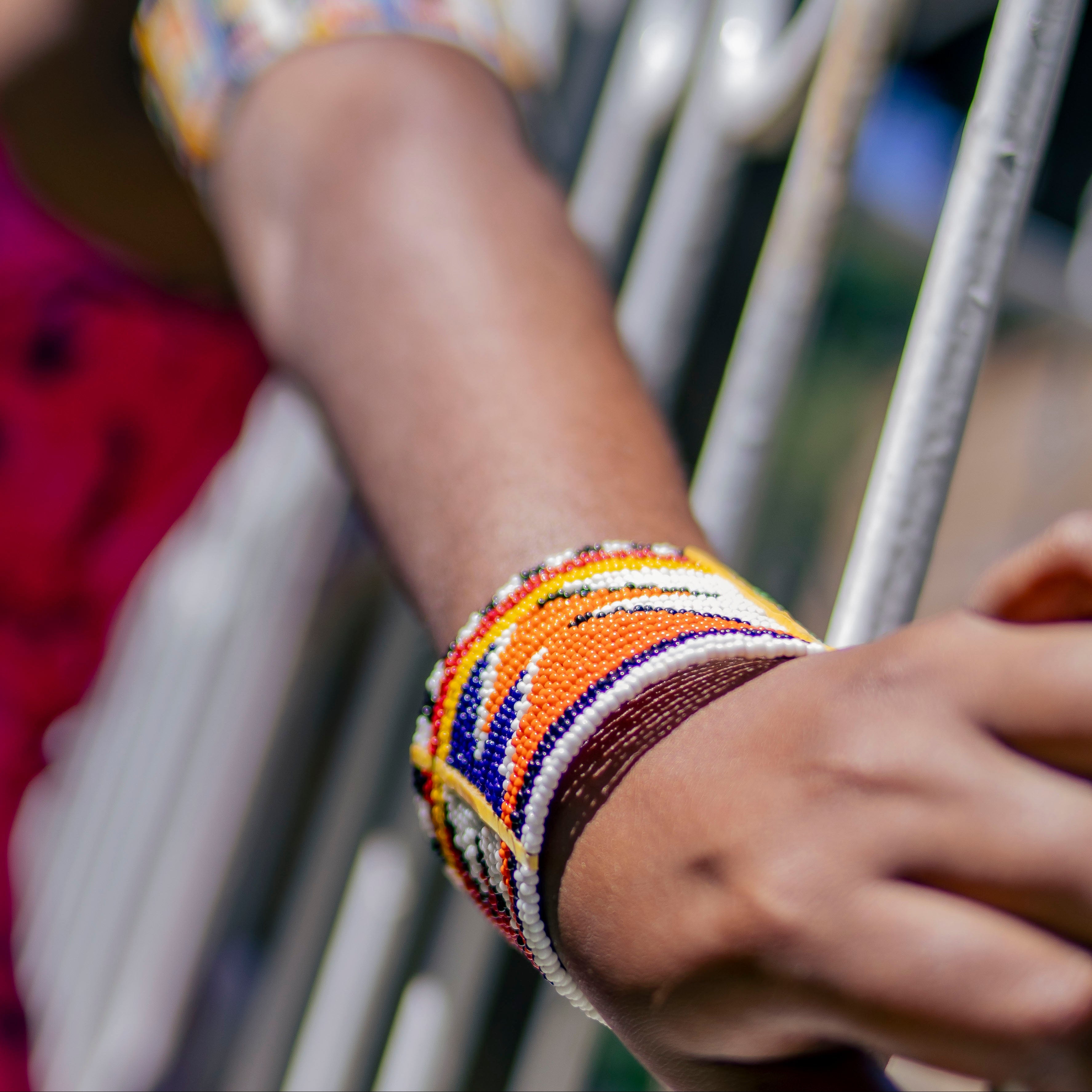 Close-up of a person's arm wearing colorful beaded bracelets with a blurred background.
