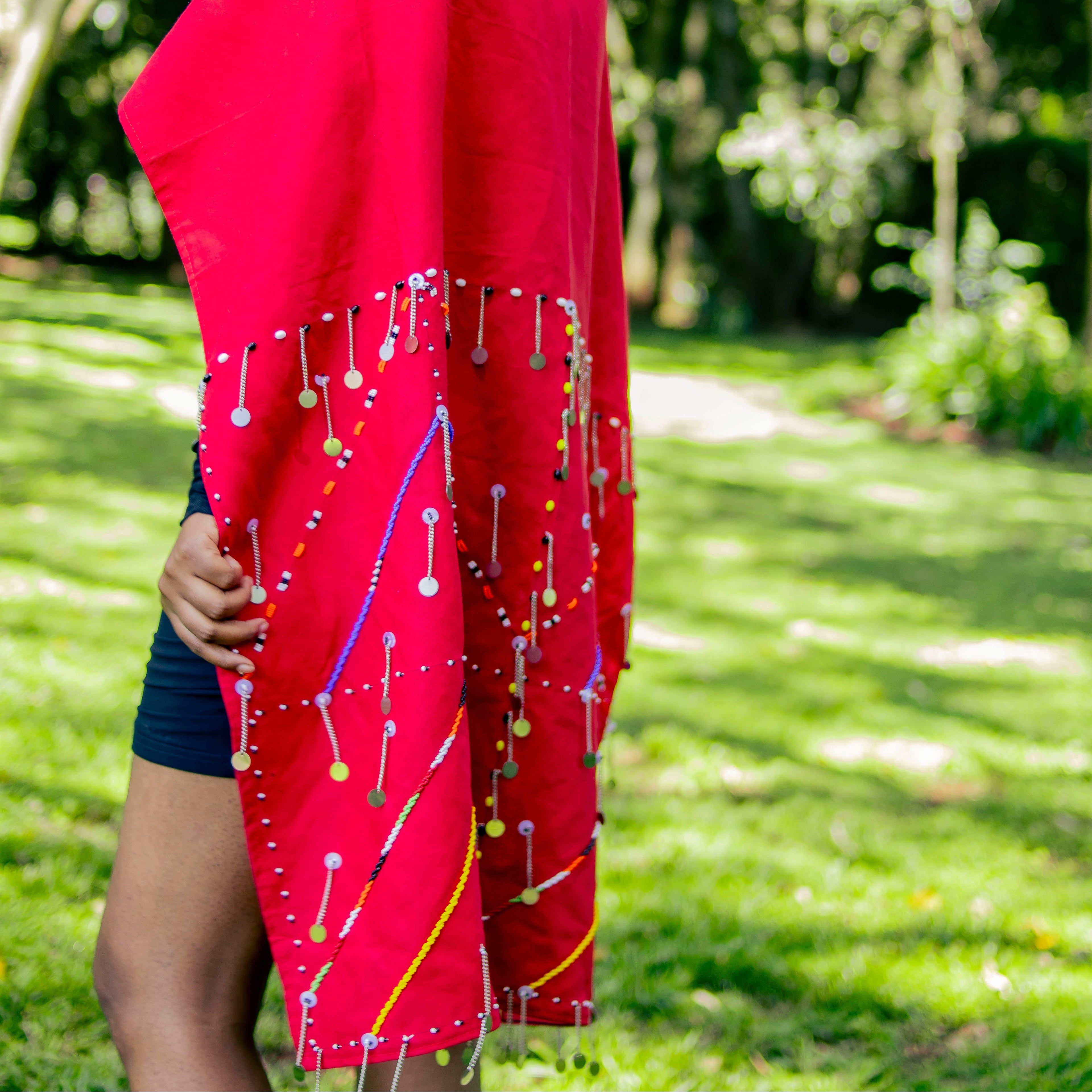 Woman wearing a red shawl with decorative pins in a park