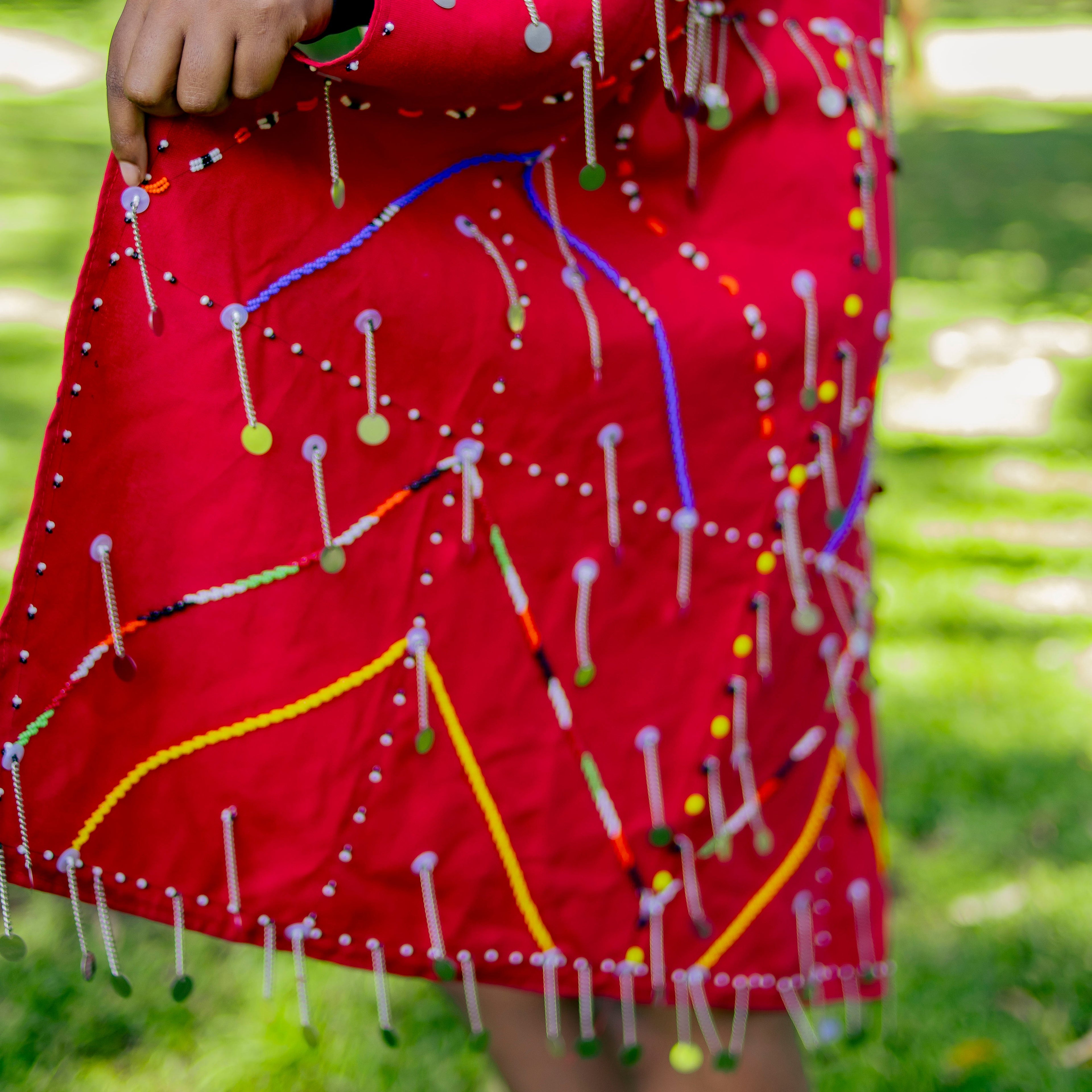 Maasai Red Cover-up garment with colorful pins on a grassy background