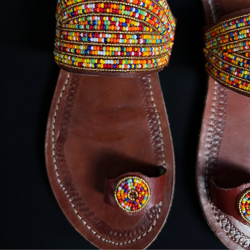 Pair of sandals with colorful beaded straps on a black background